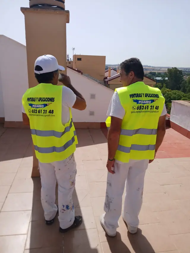 Dos operarios uniformados con chaleco de Pinturas y Aplicaciones Pizarro