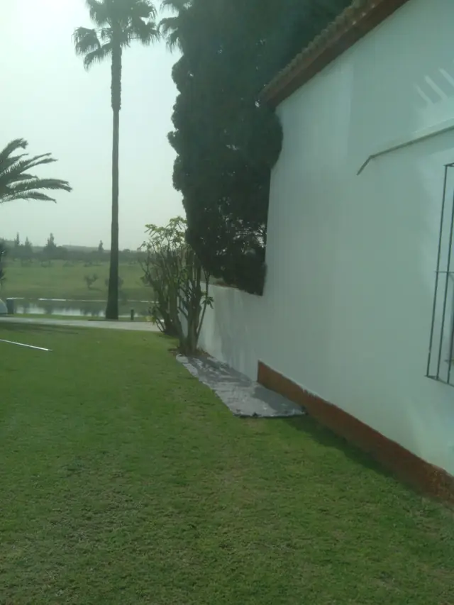 Fachada blanca de cortijo con zócalo, recién pintada