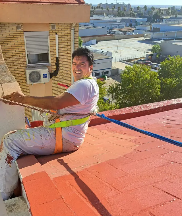 Pintor con arnés de seguridad trabajando sobre una cubierta